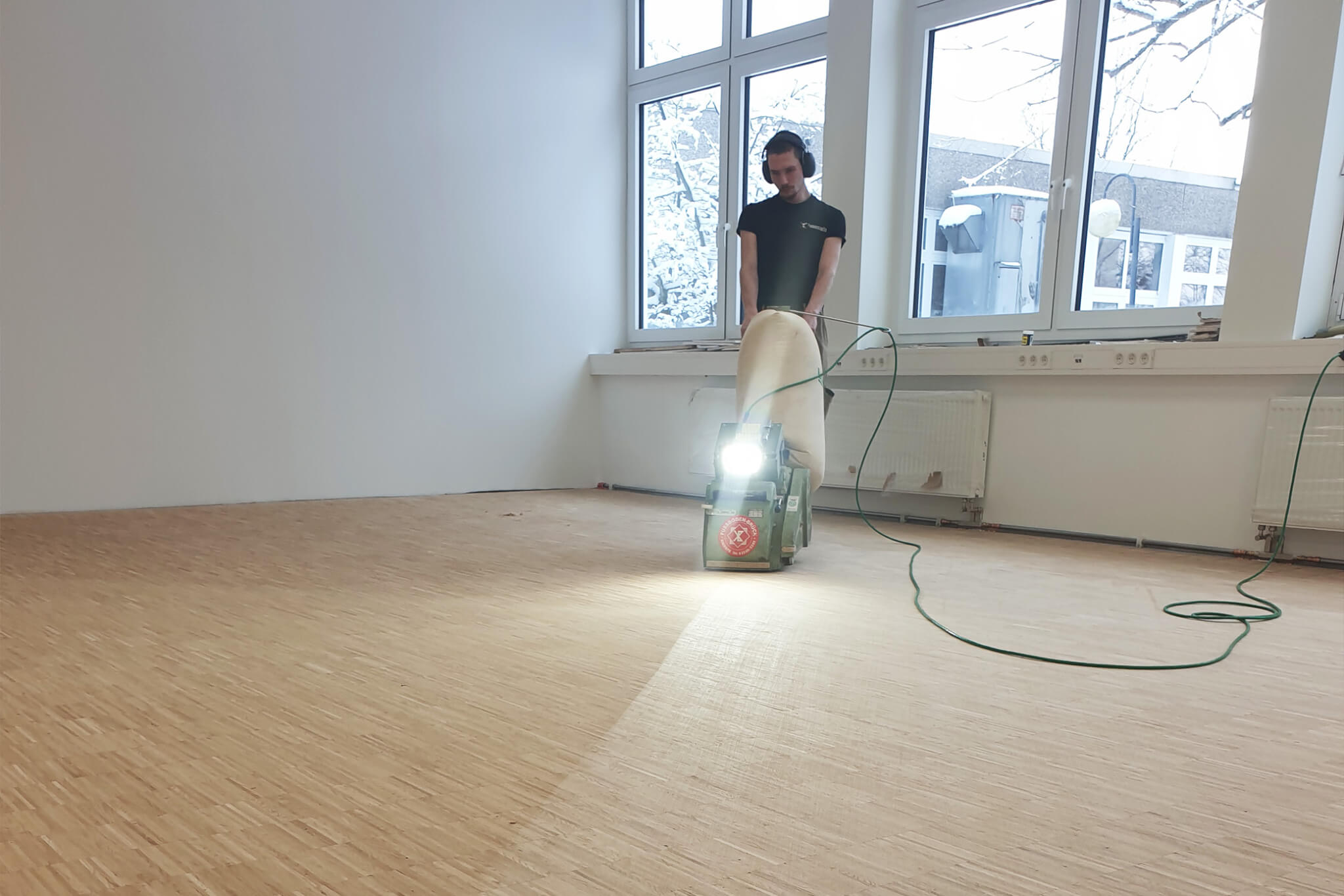 Mitarbeiter schleift den Boden mit dem Schleifgerät